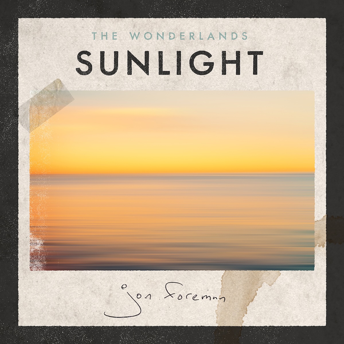 Sunlight album - On what looks like rough, light brown paper with a coffee cup stain in the bottom right, there is a photo of a beautiful golden sky over a calm, wide body of water. On the left edge, the image is worn out a bit, and there's a piece of clear tape on the top left of the image, affixing it to the paper. Above it, in the middle, it says 'The Wonderlands' in a smaller, light gray font, and 'Sunlight' in a much larger black text. Below the photo, there's a handwritten, thin pen signature of Jon Foreman. There's also a thick black border around it.