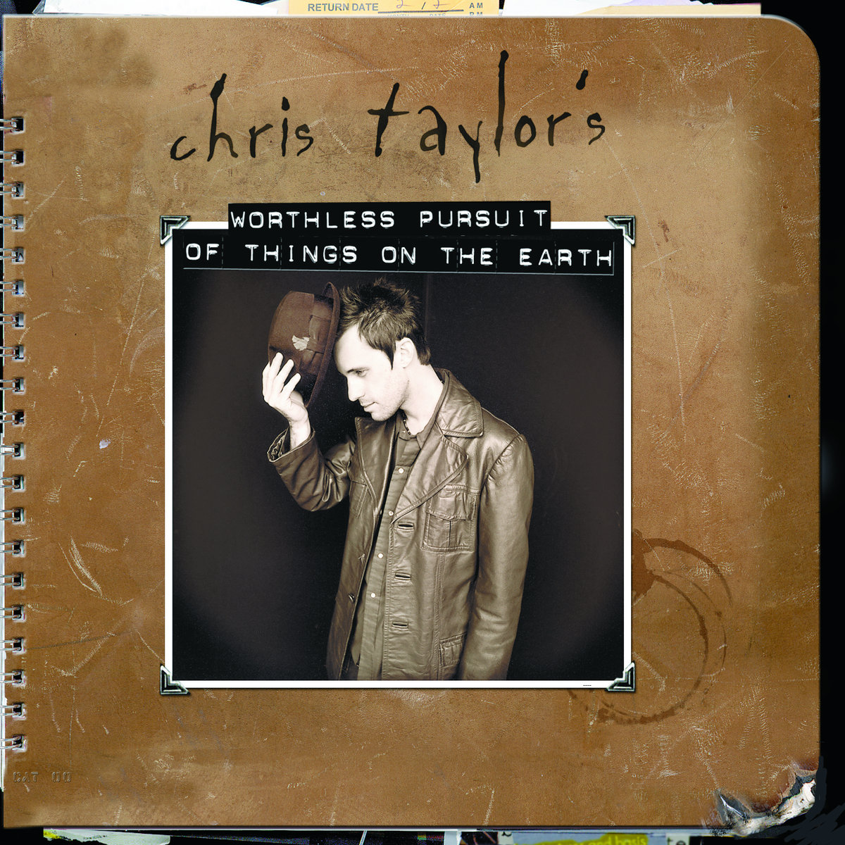 Album Art of Chris Taylor's Worthless Pursuit Of Things On The Earth album - A photo of a wire-bound notebook with a scuffed leather cover that is even missing a bit of the bottom left part. Behind can be seen some pages and other papers sticking out of the top and bottom of the notebook on the very edges of the photo. A few coffee cup stains are also on the leather, just to the bottom right of a photo affixed to the front of the cover.</body></html>