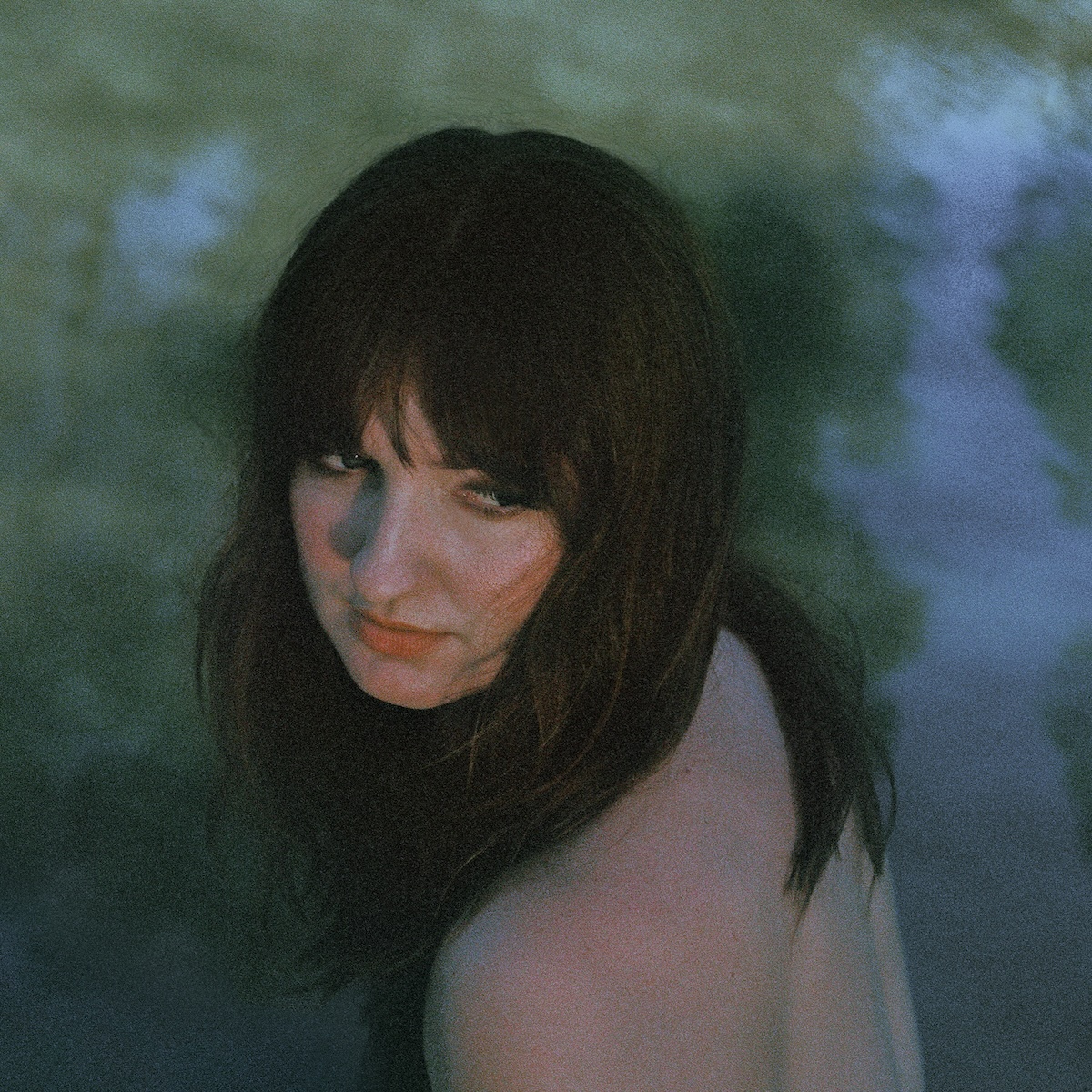 Album Art of Madison Cunningham's Ace album - A photo of a woman from slightly above in front of or in some sort of body of water, as the trees and sky are reflecting off the water behind her. The photo is pretty grainy, but her dark brown hair is covering her shoulders. She is facing away from the camera but looking back over her shoulder. We see her bare upper back and shoulder in the bottom of the frame.</body></html>