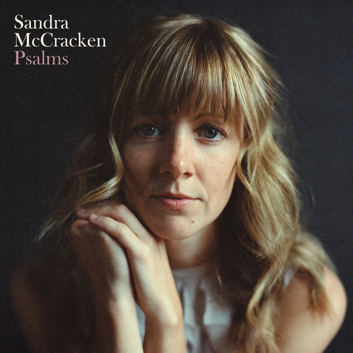 Album Art of Sandra McCracken's Psalms album - A close-up photo of a middle-aged woman from the shoulders up, with her hands clasped together to the left of her chin. Her blone-brown hair goes down past her shoulders. She is leaning in and staring straight into the camera with a fairly blank expression. The shoulders are out of focus. The background is a dark gray, nearly black.</body></html>