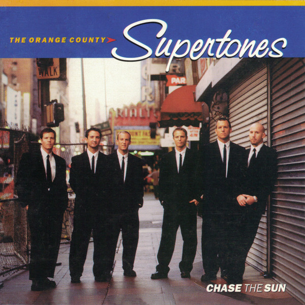 Album Art of The O.C. Supertones's Chase The Sun album - Six young men are photographed standing on a city sidewalk with a theater marquee behind them and a metal door on the front of a shop off to their right. One of them is leaning against the metal door. They are all wearing white shirts and black ties, and suits and black pants that look a bit baggy. They're all looking at the camera with mostly blank expressions, a few slightly smiling.</body></html>