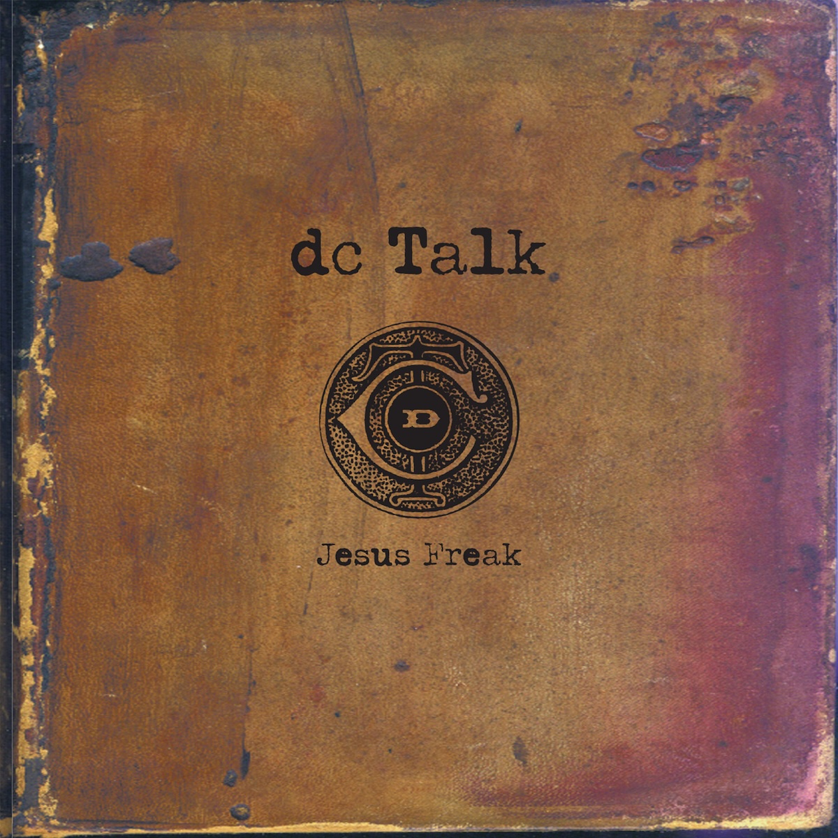 Album Art of DC Talk's Jesus Freak album - A square album cover that looks like an old, aged, leather-bound book cover with it coming apart at the edges and wear and discoloration on different portions closest to the edge. In the middle, printed in black is a circle stamp with a 'dcT' design, and above it in a large, work typewriter font is the group name, and below in smaller font is the album title.